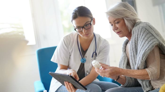 Elderly patient and healthcare professional looking at a tablet