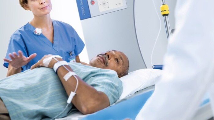 Mid shot of a patient lying down with a female doctor standing besides him