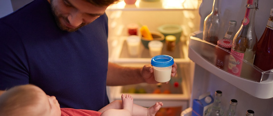 Father storing breast milk in fridge