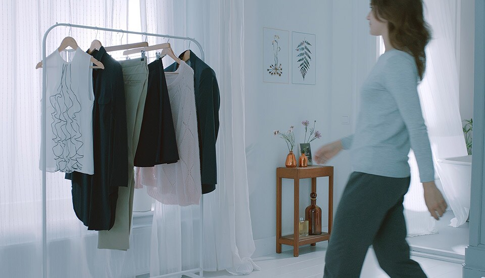 a woman walking towards clothing rack